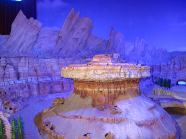 A much larger 1:8 model of Radiator Springs model is behind the smaller Carsland model. A much larger 1:8 model of Radiator Springs model is behind the smaller Carsland model.
